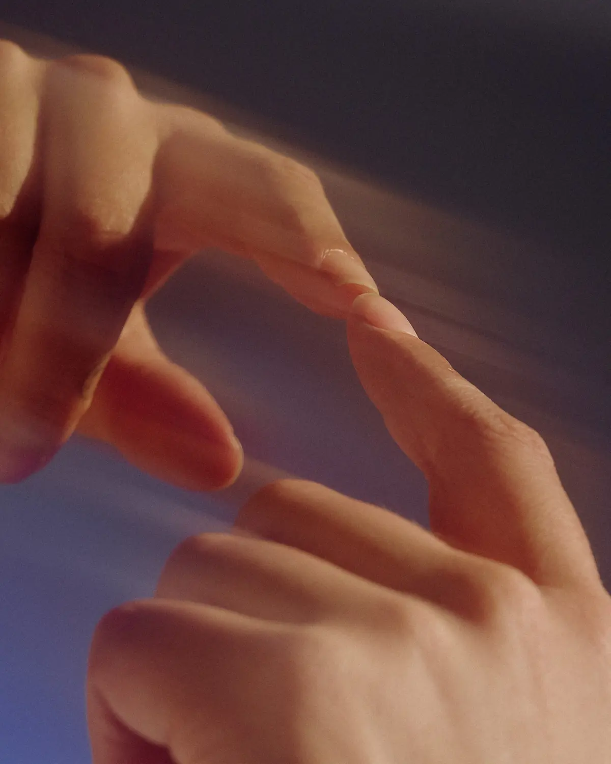 Close-up of two hands, fingertips almost touching, against a blurred violet background