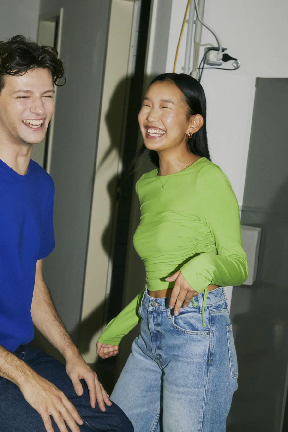 Two friends laughing together in a white corridor
